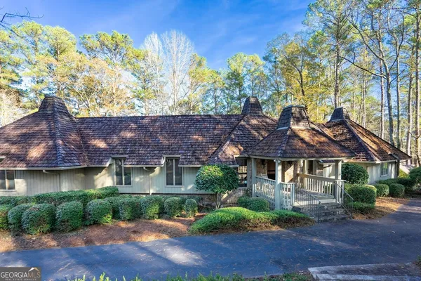 a front view of a house with a yard and a large tree