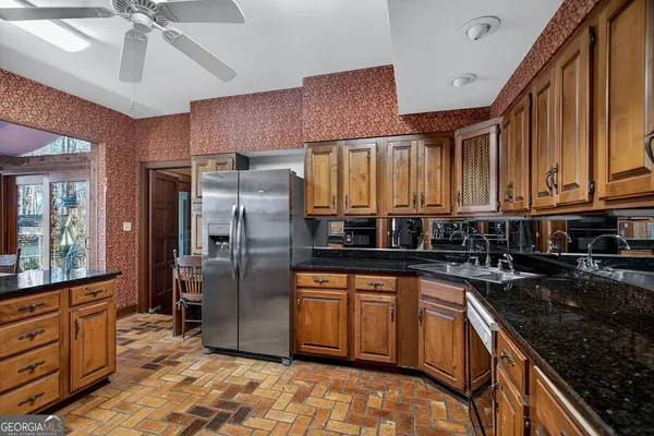 a kitchen with stainless steel appliances granite countertop a refrigerator a stove and a sink with cabinets