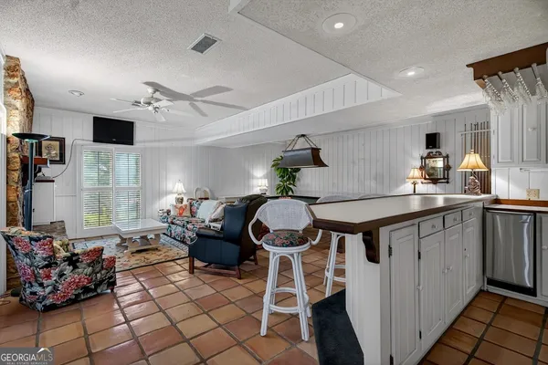 a kitchen with stainless steel appliances kitchen island granite countertop a sink dishwasher a dining table and chairs with wooden floor