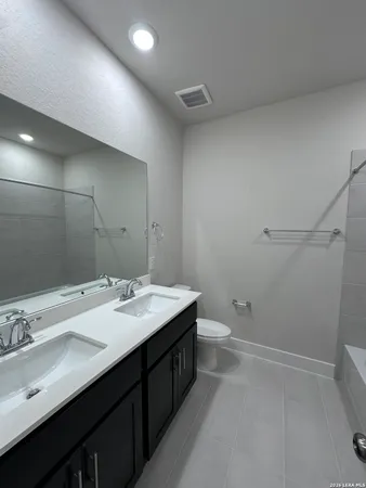 a bathroom with a double vanity sink toilet and a mirror