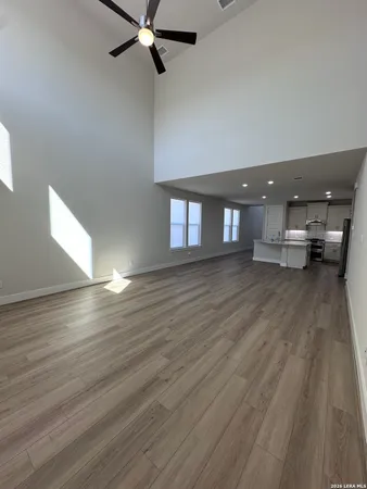 a view of empty room with wooden floor and fan