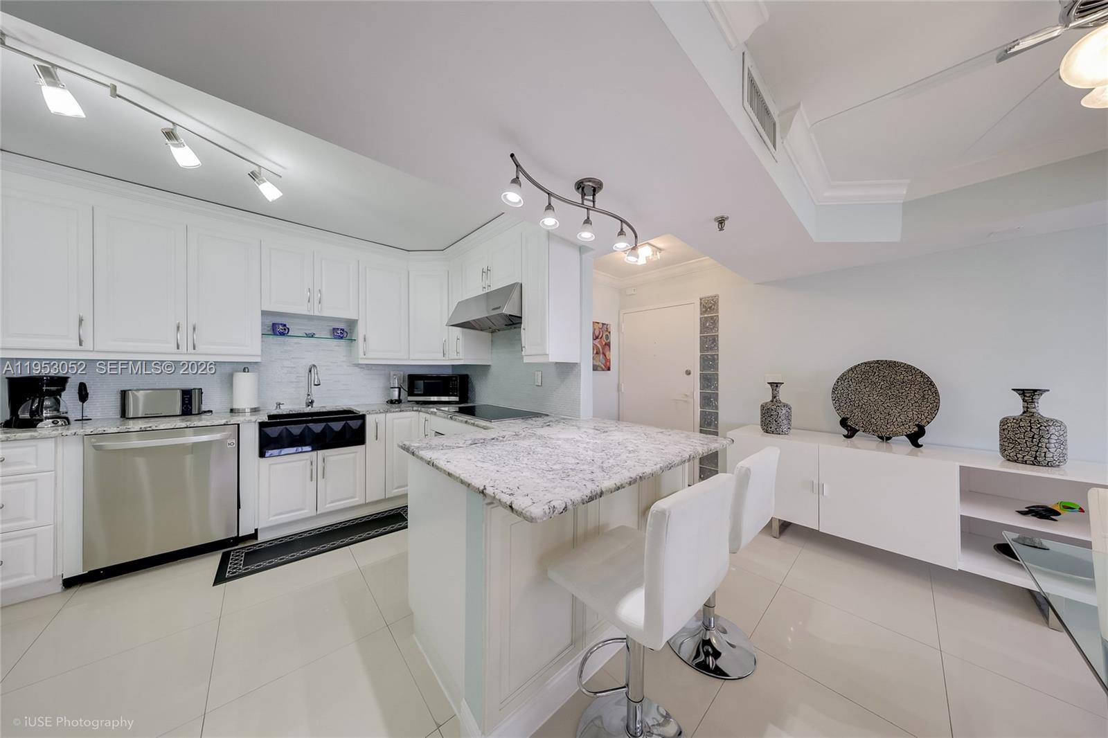 9341 Collins Avenue, Unit 503 Surfside, FL 33154 - Photo 8 of 35 a kitchen with white cabinets and sink