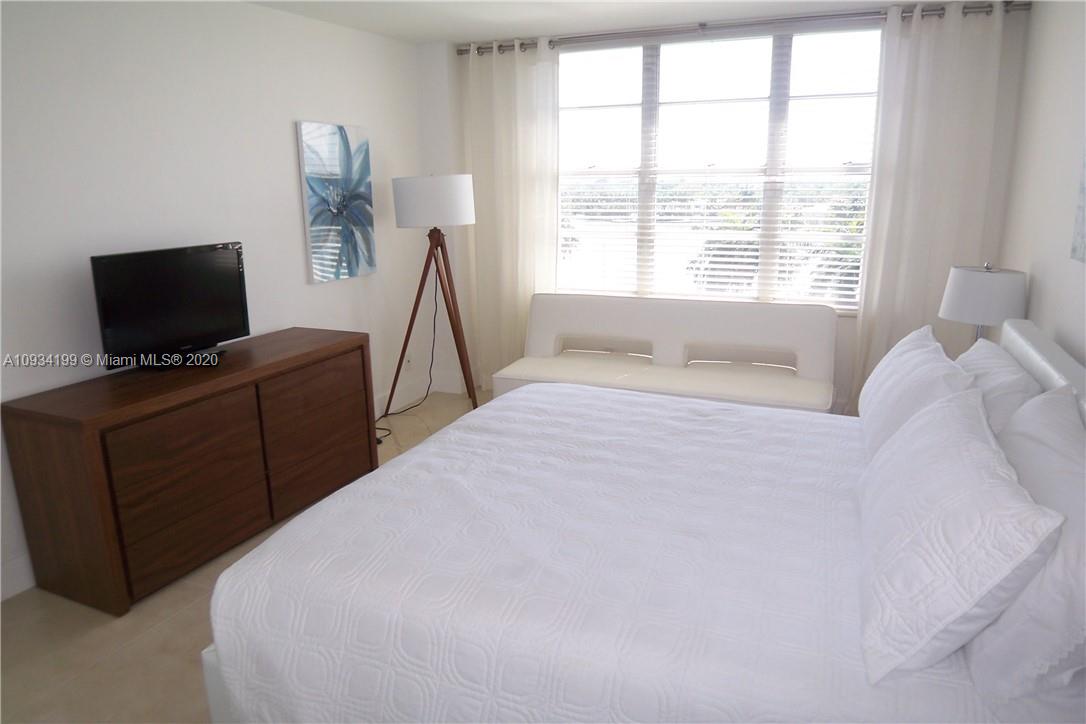 5161 Collins Avenue, Unit 806 Miami Beach, FL 33140 - Photo 23 of 52 a bedroom with a bed and a flat tv screen on a dresser