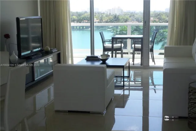 a living room with couches a flat screen tv and a floor to ceiling window