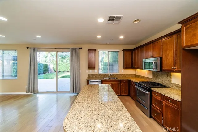 a large kitchen with stainless steel appliances granite countertop plenty wooden cabinets counter space and a window