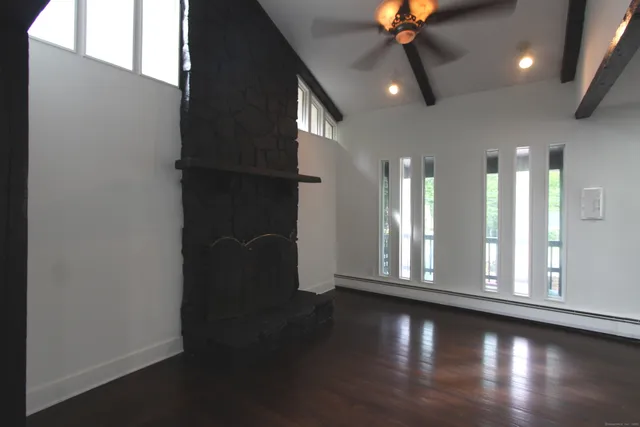 an empty room with wooden floor fan and window
