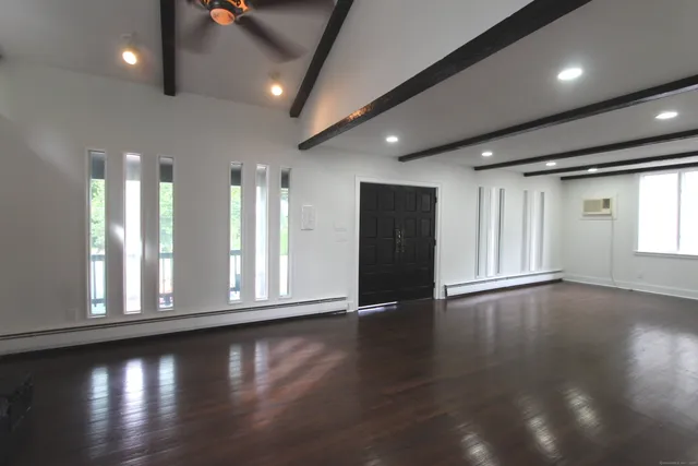 an empty room with wooden floor and windows
