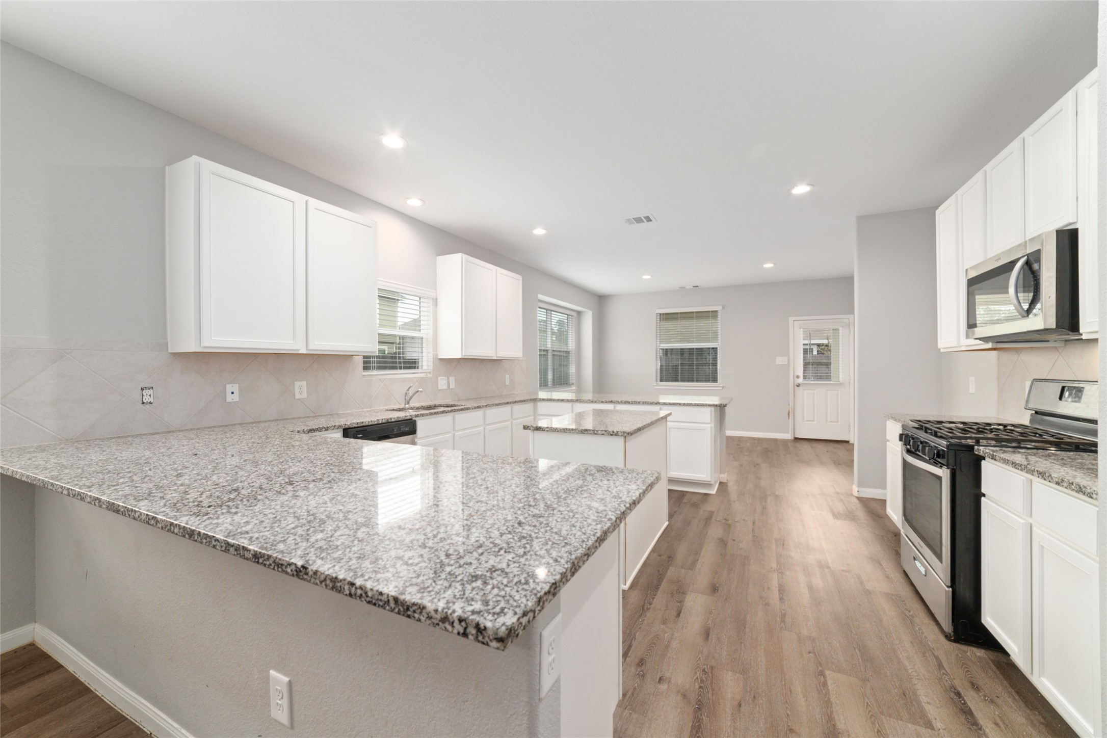 2209 Raider Drive Conroe, TX 77301 - Photo 7 of 27 a large kitchen with stainless steel appliances granite countertop a lot of counter space and wooden floor
