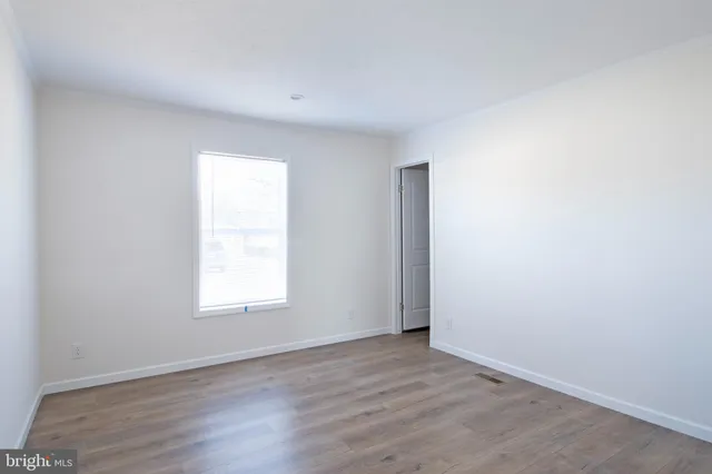 an empty room with wooden floor and window