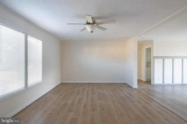 an empty room with wooden floor fan and windows