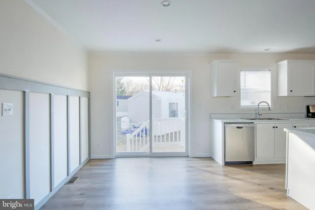 a large white kitchen with granite countertop a dishwasher a stove a refrigerator with white cabinets and wooden floor