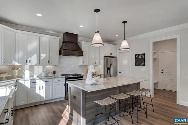 a kitchen with stainless steel appliances a dining table chairs and stove top oven