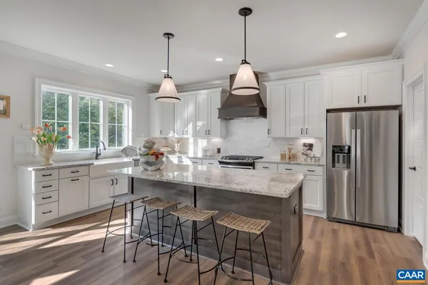 a kitchen with stainless steel appliances a sink a stove a refrigerator a center island and a window