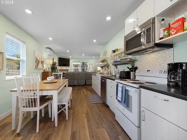 a kitchen with stainless steel appliances kitchen island granite countertop a stove top oven a sink a dining table and chairs with wooden floor