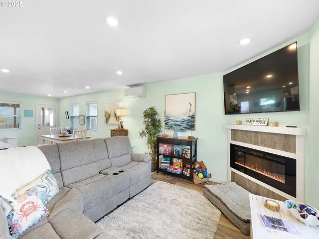 a living room with furniture a flat screen tv and a fireplace with kitchen view