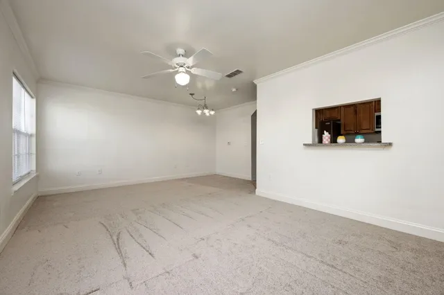 an empty room with windows and chandelier fan