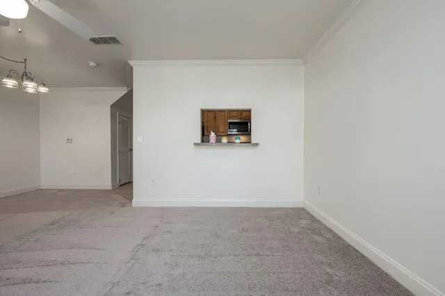 an empty room with chandelier fan and windows