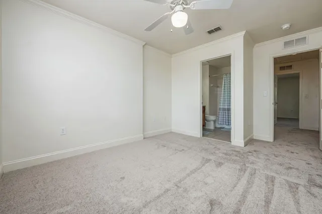 an empty room with a chandelier fan and windows