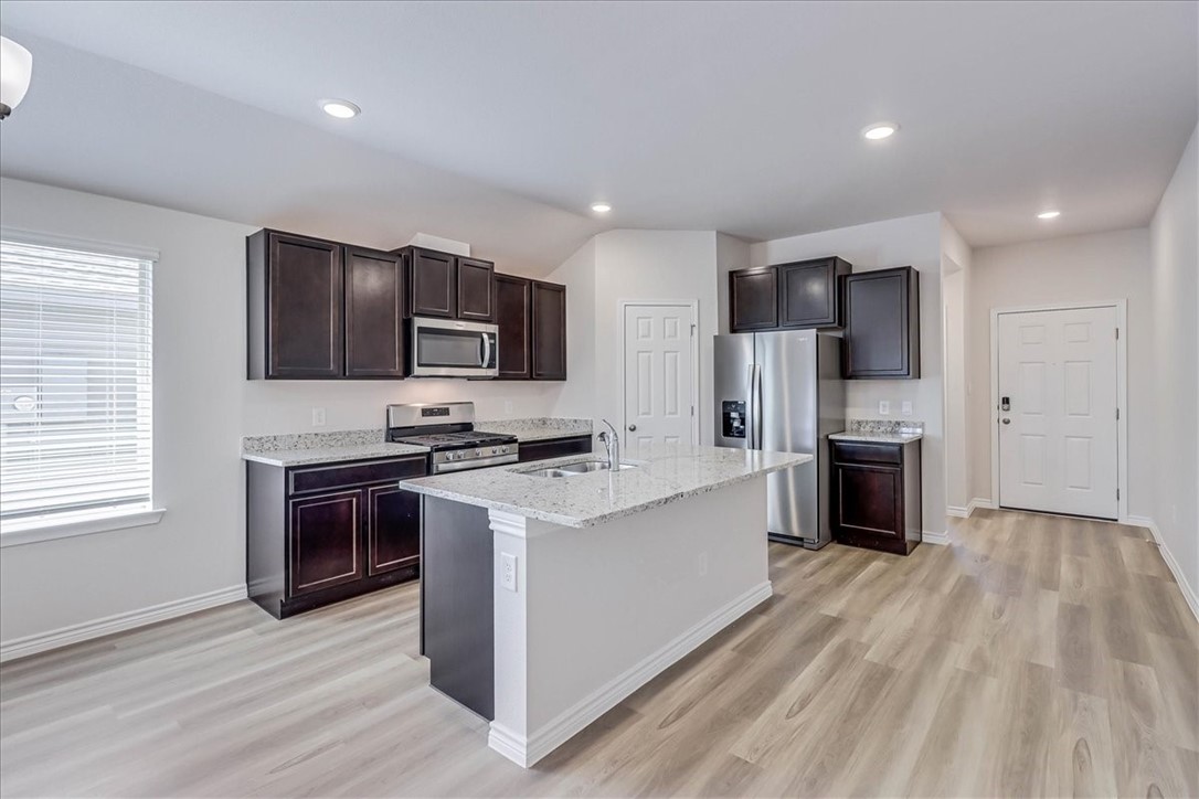 1634 Comfy Way Corpus Christi, TX 78418 - Photo 11 of 39 a kitchen with stainless steel appliances a stove top oven a sink a refrigerator white cabinets and wooden floor