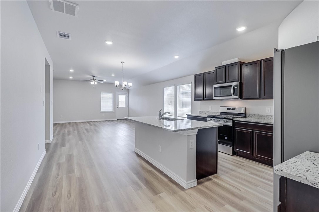 1634 Comfy Way Corpus Christi, TX 78418 - Photo 15 of 39 a large kitchen with stainless steel appliances a large counter top stove a sink dishwasher and a refrigerator with wooden floor