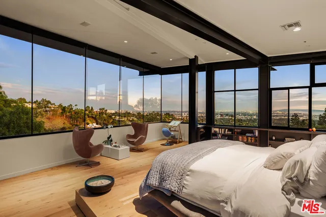 a bedroom with a bed and large windows