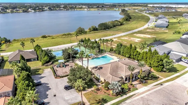 an aerial view of a house with swimming pool lawn chairs and large trees