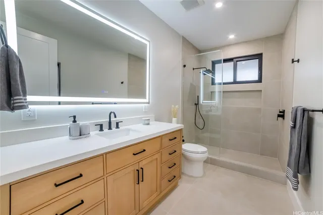 a kitchen with stainless steel appliances kitchen island granite countertop a sink a stove a refrigerator and white cabinets with wooden floor