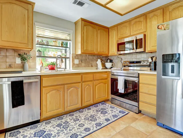 a kitchen with stainless steel appliances granite countertop a refrigerator a sink and wooden cabinets