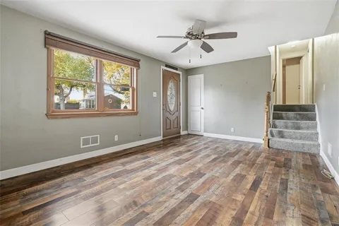 a view of an empty room with a window and wooden floor