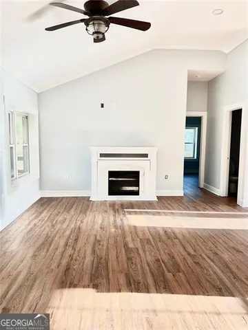 a view of empty room with wooden floor and fireplace