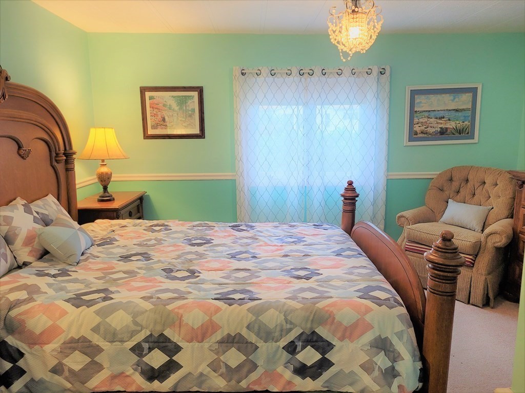 62 Longboat Road Wareham, MA 02576 - Photo 16 of 32 a bedroom with a bed and a chandelier