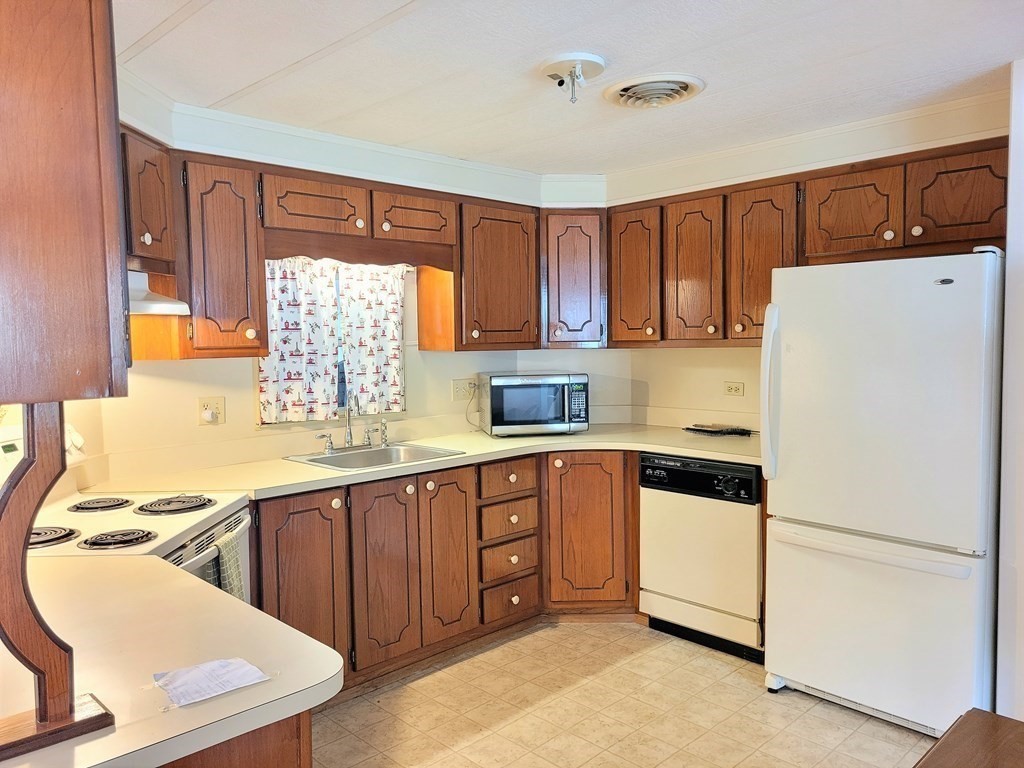 62 Longboat Road Wareham, MA 02576 - Photo 9 of 32 a kitchen with a refrigerator a sink and cabinets