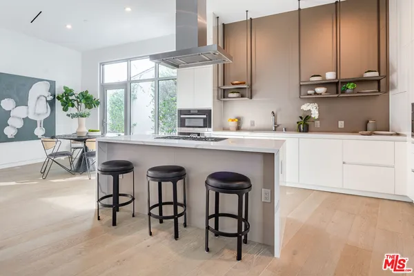 a kitchen with stainless steel appliances granite countertop white cabinets a stove a sink and a refrigerator