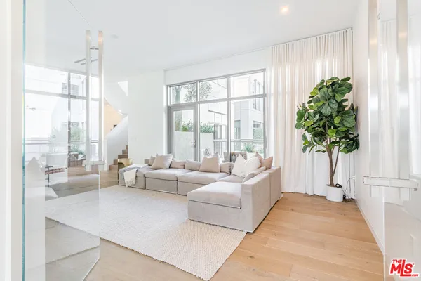 a living room with furniture and a large window with potted plants