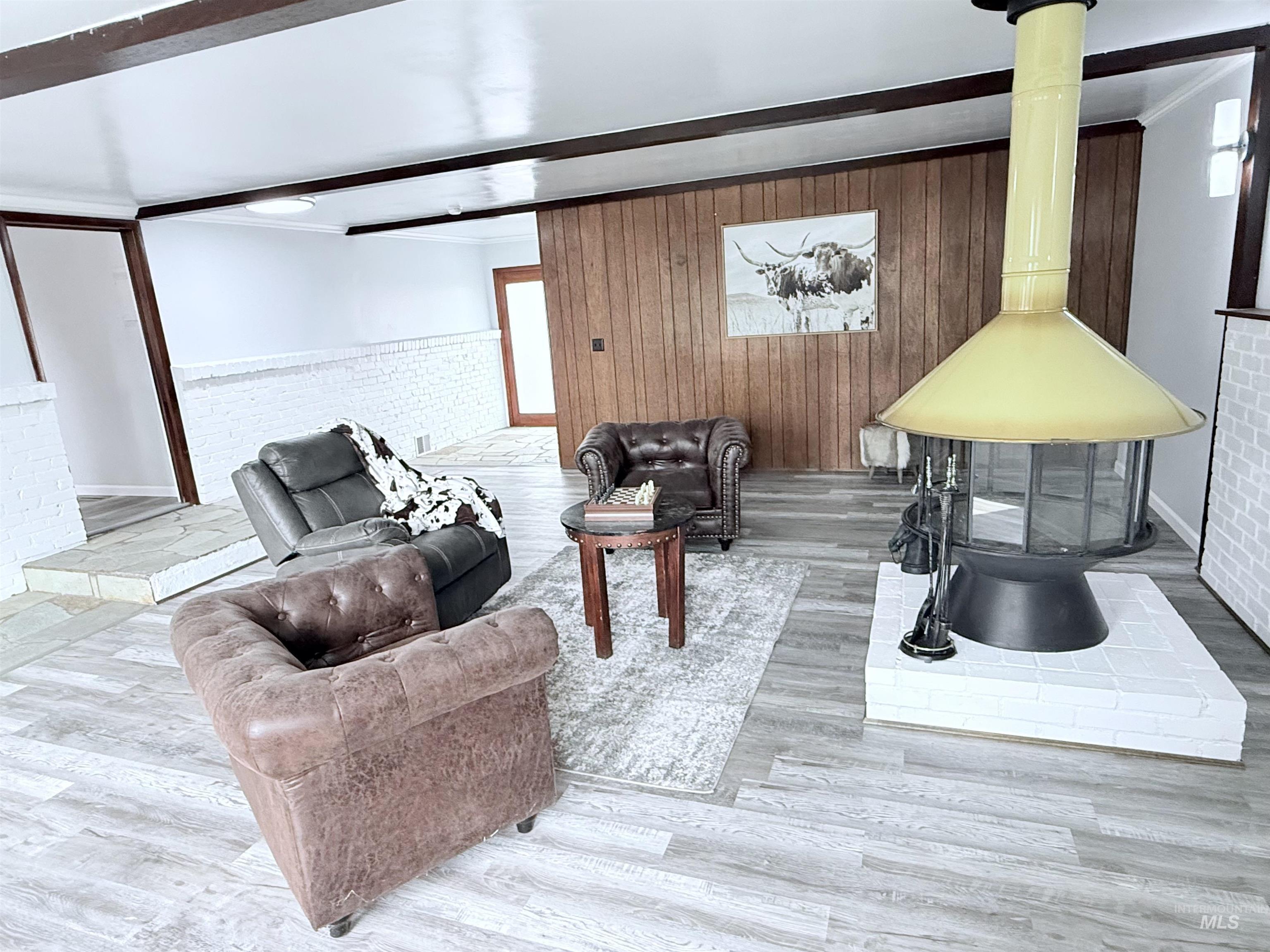 202 East Avenue Wendell, ID 83355 - Photo 16 of 24 Living room with a wainscoted wall, wood finished floors, wood walls, beamed ceiling, and ornamental molding