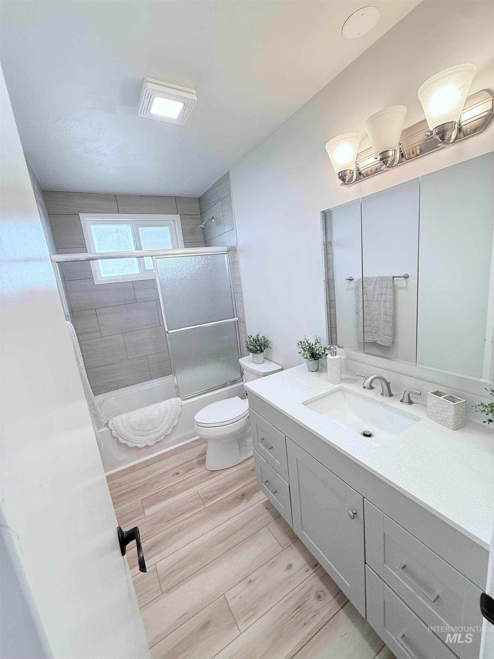 202 East Avenue Wendell, ID 83355 - Photo 10 of 24 Bathroom featuring bath / shower combo with glass door, vanity, and light wood-type flooring