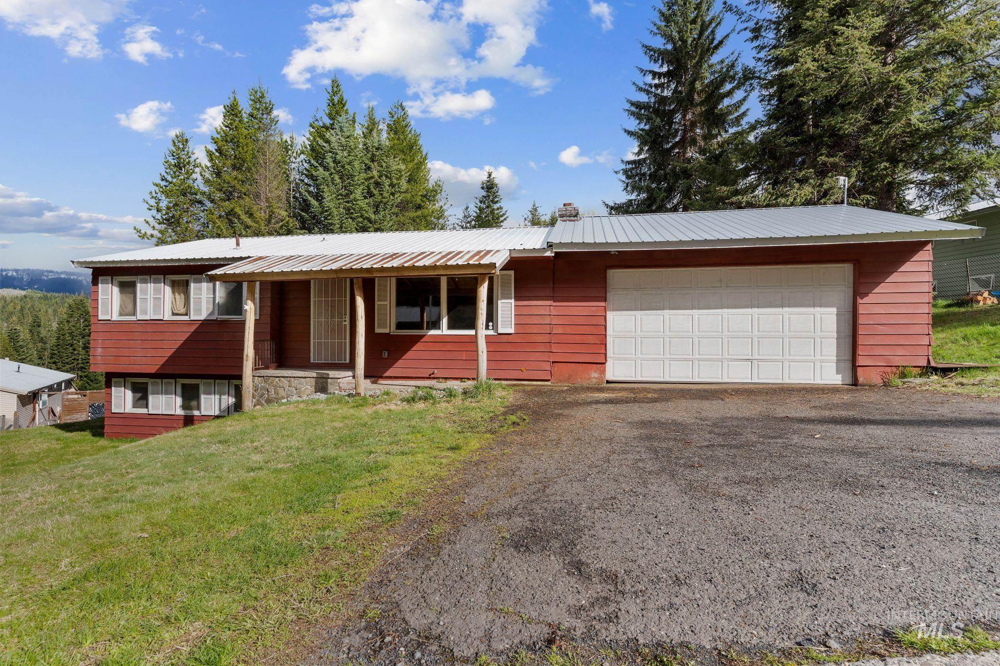 Red siding exterior with a metal roof and an attached white panel garage door