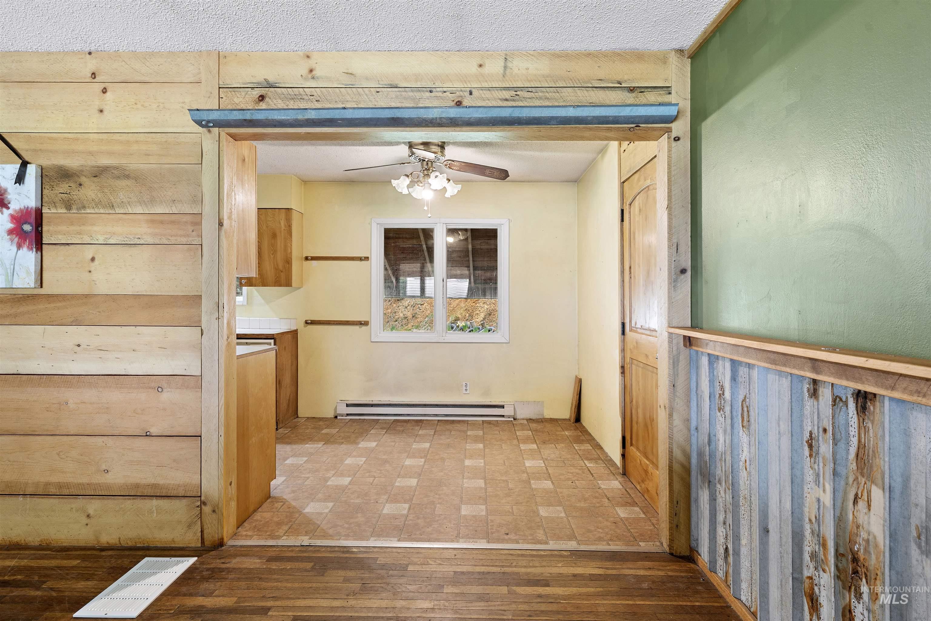 145 Timberline Drive Pierce, ID 83546 - Photo 13 of 39 The entry features wood-finish flooring and a wood plank wall, opening to a tiled area with a window and ceiling fan