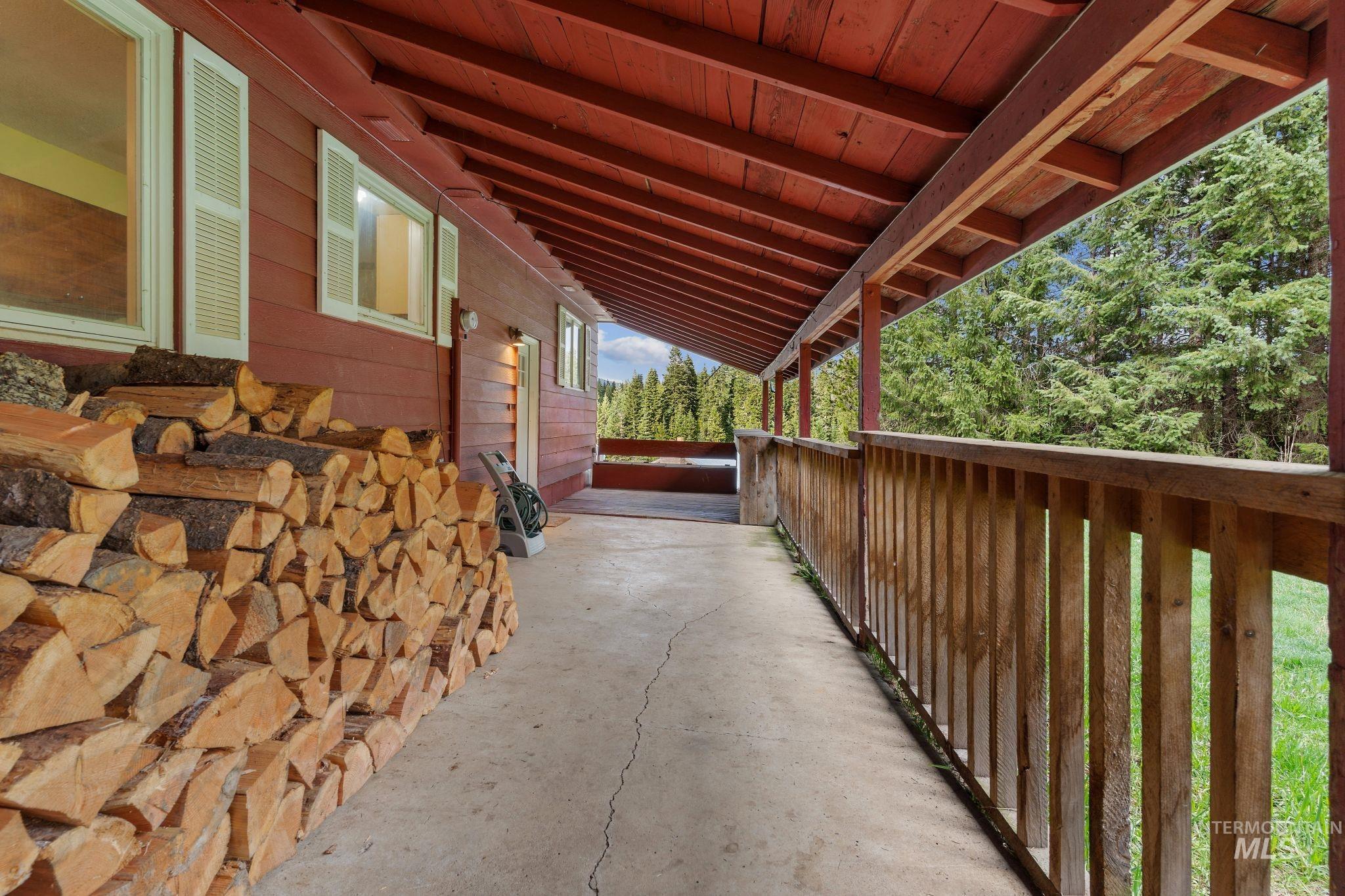 145 Timberline Drive Pierce, ID 83546 - Photo 23 of 39 Covered exterior porch with wood-finish siding, exposed red rafter tails, and a rustic wooden railing