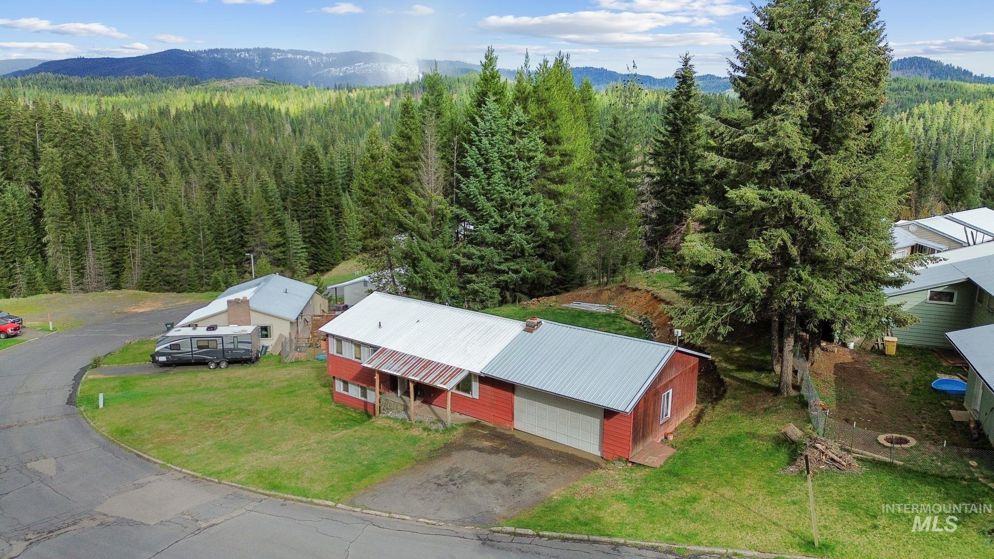 145 Timberline Drive Pierce, ID 83546 - Photo 34 of 39 Red-sided residence featuring a covered front porch and an attached garage with a white door