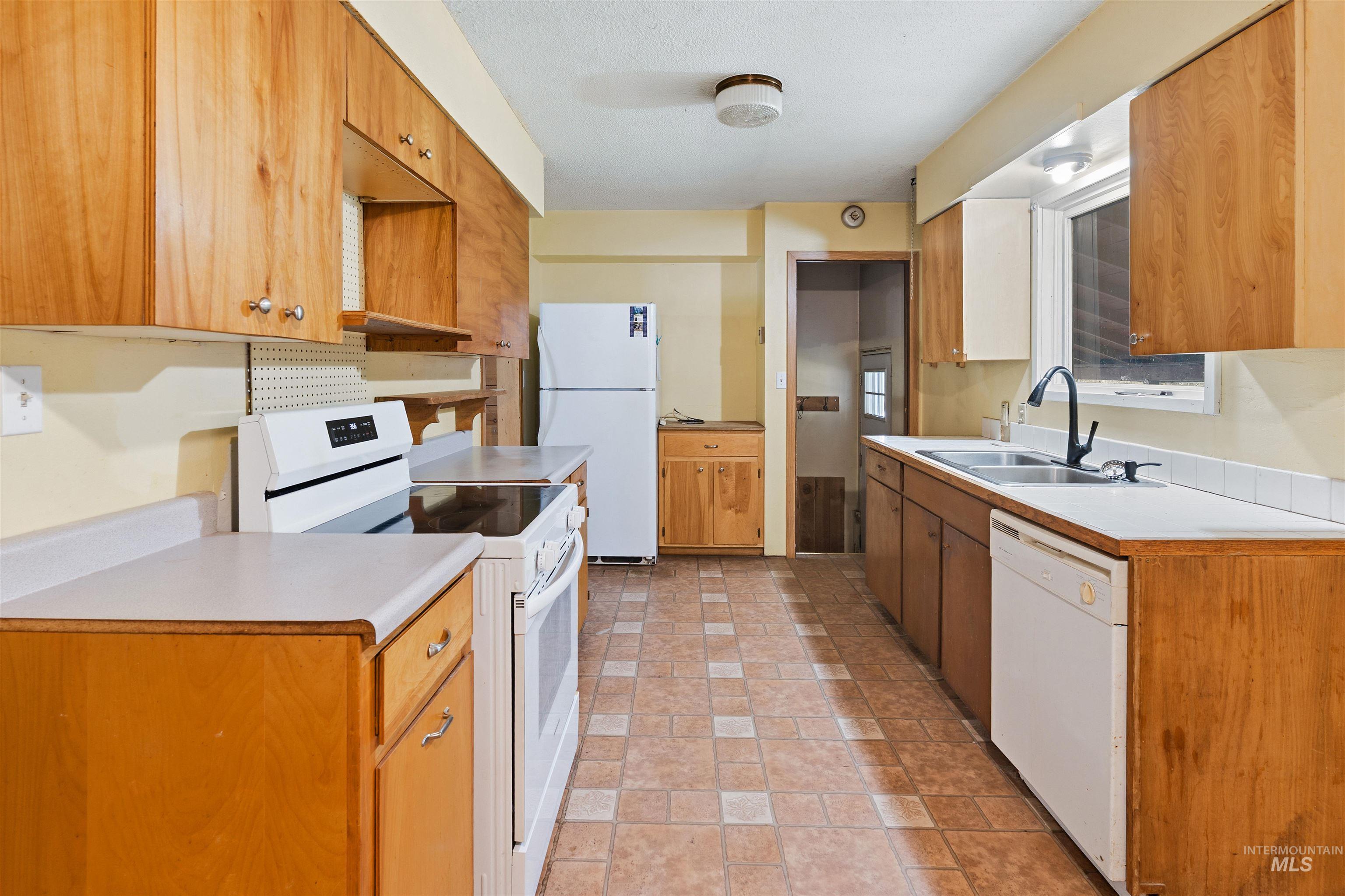 145 Timberline Drive Pierce, ID 83546 - Photo 6 of 39 Kitchen featuring abundant wood cabinetry, tile flooring, and white countertops