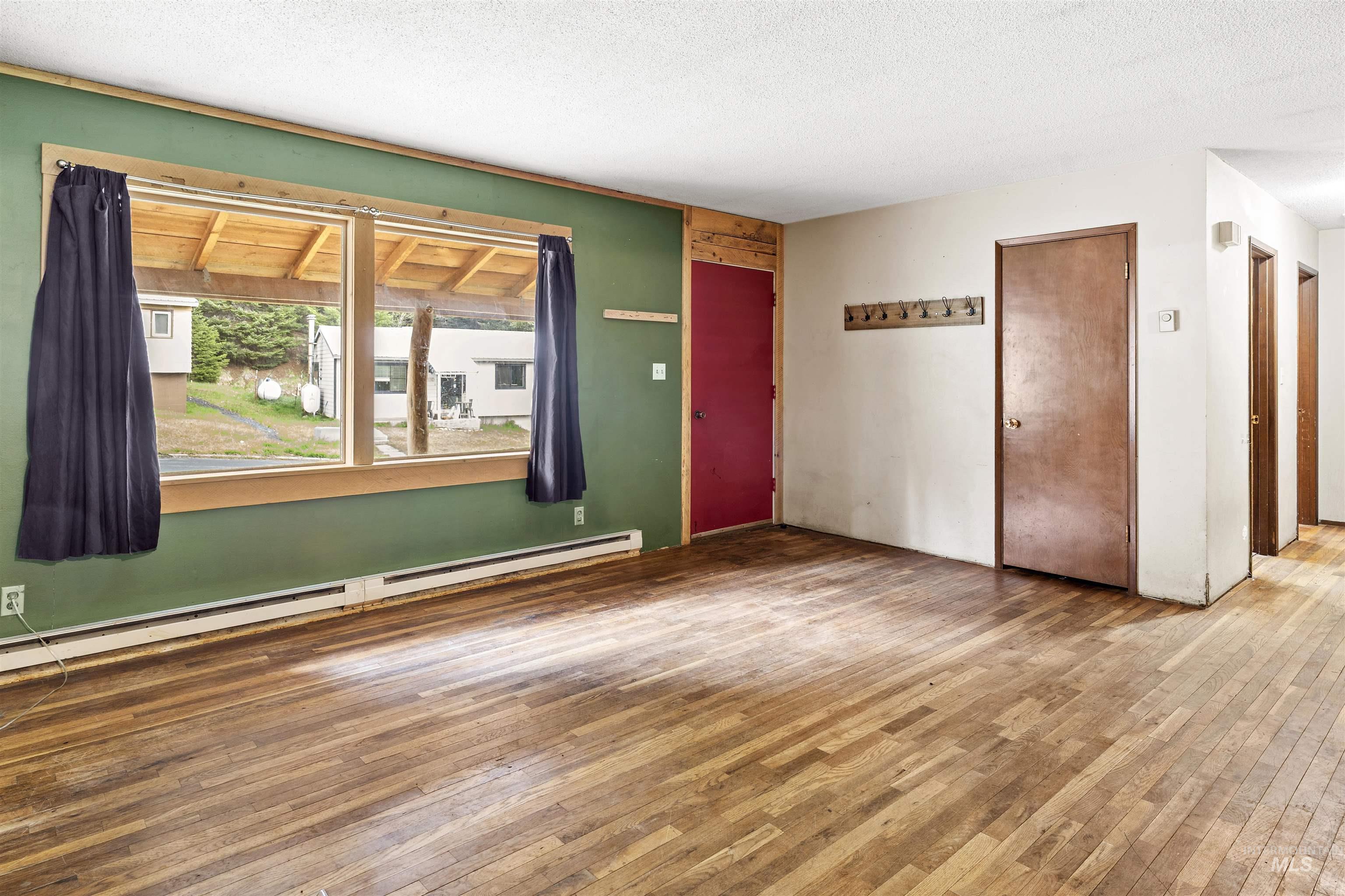 145 Timberline Drive Pierce, ID 83546 - Photo 7 of 39 Open concept living area featuring wood-finish flooring, a large window with wood trim, and baseboard heating