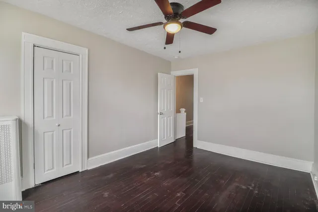 an empty room with wooden floor fan and windows