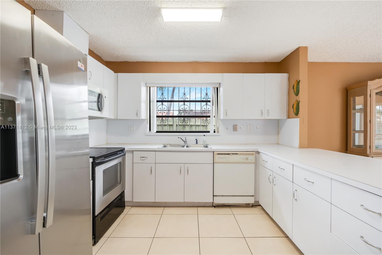 13817 Southwest 21st Terrace Miami, FL 33175 - Photo 12 of 37 a kitchen with white cabinets stainless steel appliances and a window