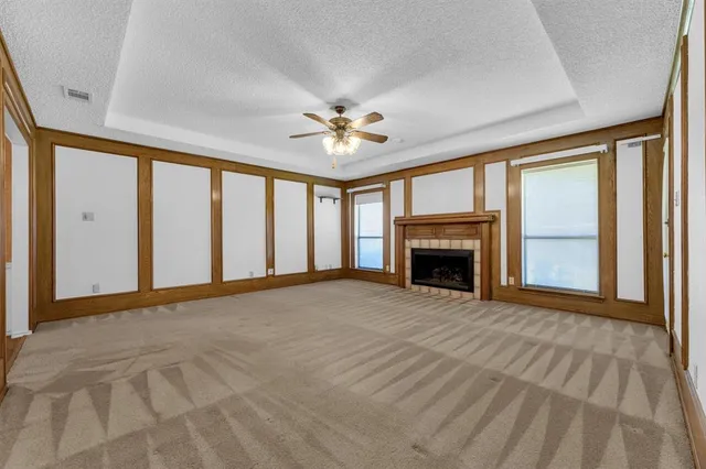 a view of an empty room with chandelier fan and a fireplace