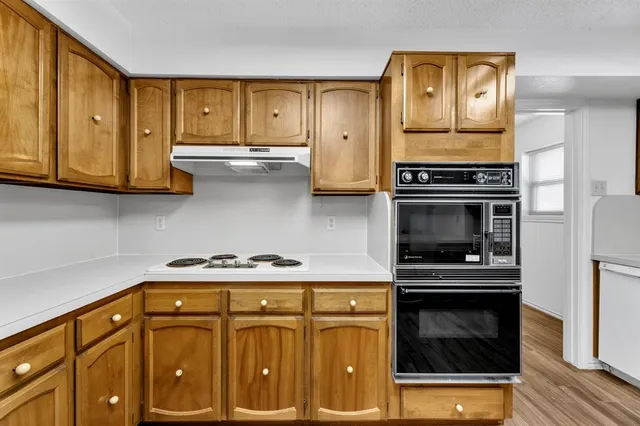 a kitchen with granite countertop cabinets stainless steel appliances and wooden floor