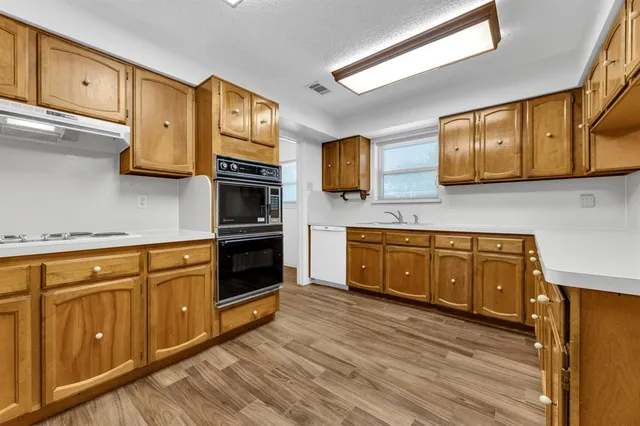 a kitchen with stainless steel appliances granite countertop a stove a sink and a microwave