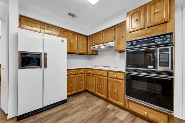 a kitchen with cabinets stainless steel appliances and wooden floor