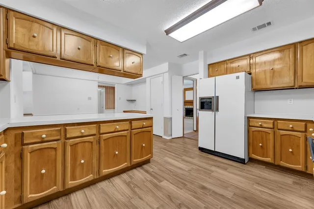 a kitchen with granite countertop wooden cabinets a refrigerator a sink and wooden floors