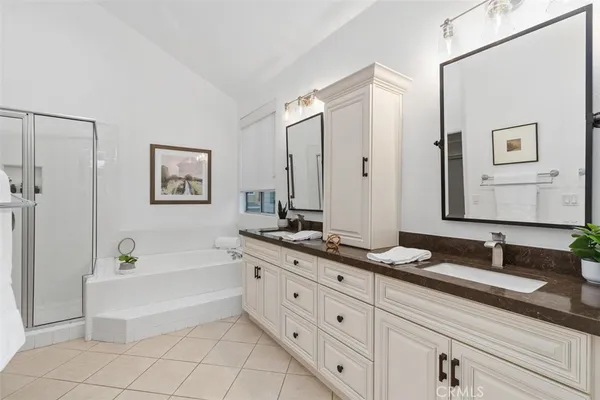 a bathroom with a double vanity sink a mirror a bathtub and a shower